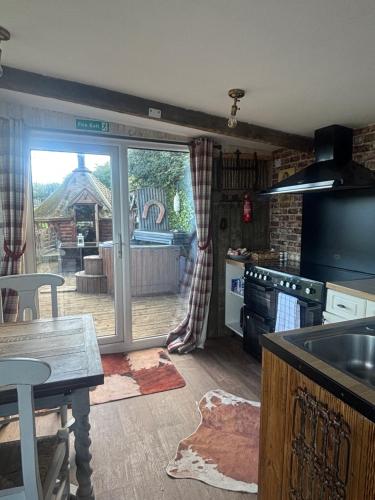 a kitchen with a large sliding glass door to a yard at Bridie -rose with wood tub country retreat in Kington
