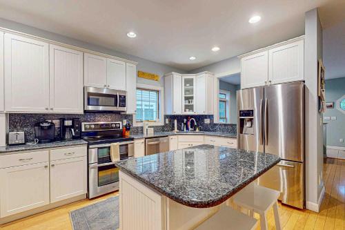 a kitchen with white cabinets and a stainless steel refrigerator at Ocean Mist --- 10 Ocean Mist Dr in Ocean View