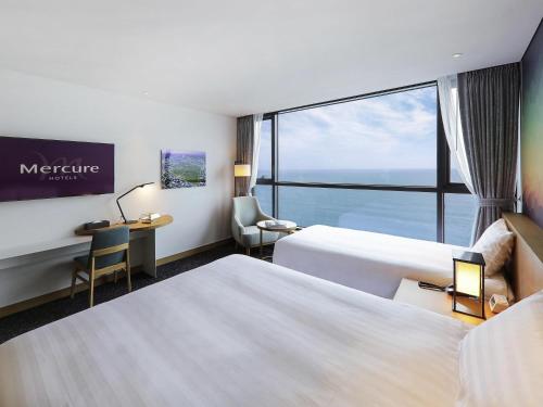 a hotel room with two beds and a large window at Mercure Ambassador Ulsan in Ulsan