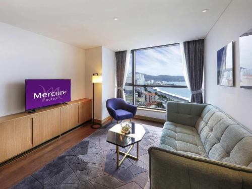 a living room with a couch and a tv at Mercure Ambassador Ulsan in Ulsan