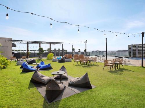 a patio with tables and chairs on the grass at Novotel Suites Yogyakarta Malioboro in Yogyakarta