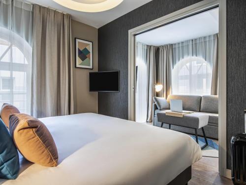 a hotel room with a large bed and a chair at Aparthotel Adagio Lille Centre Grand Place in Lille