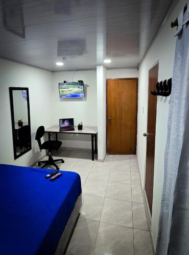 a room with a bed and a desk with a laptop at Fly N' Stay Bogota in Bogotá