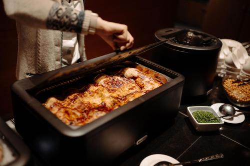 a person preparing a dish of food in a pan at Familien- & Gartenhotel Theresia 4-Sterne Superior in Saalbach Hinterglemm