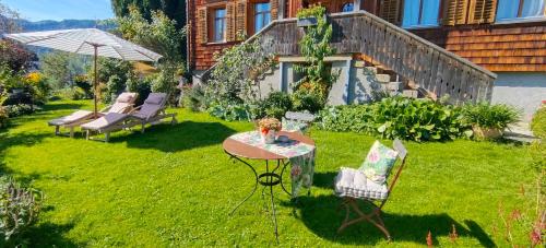 a garden with a table and chairs and an umbrella at Ferienwohnung Ritter in Schwarzenberg im Bregenzerwald