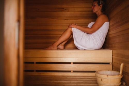 a woman is sitting in a sauna at Golden Lakes Village Ardennes in Boussu-lez-Walcourt