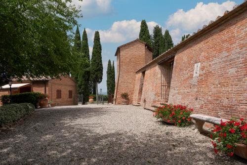 a courtyard of a brick building with trees and flowers at Castello di Leonina Relais - Adults Only in Siena