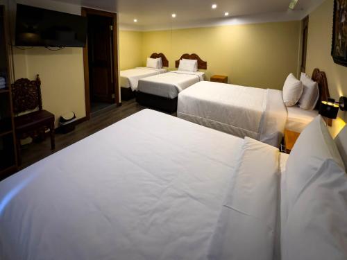 a hotel room with three beds with white sheets at Santuario Machupicchu in Machu Picchu