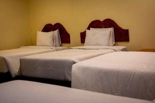 three beds in a hotel room with white sheets at Santuario Machupicchu in Machu Picchu