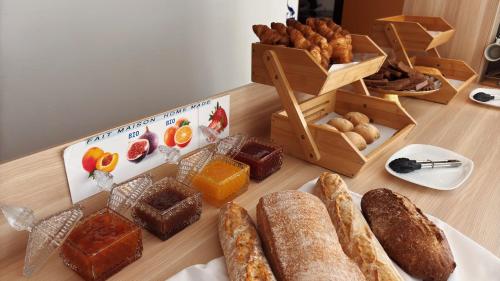 a table topped with different types of bread and pastries at Kyriad Direct Arpajon in Arpajon