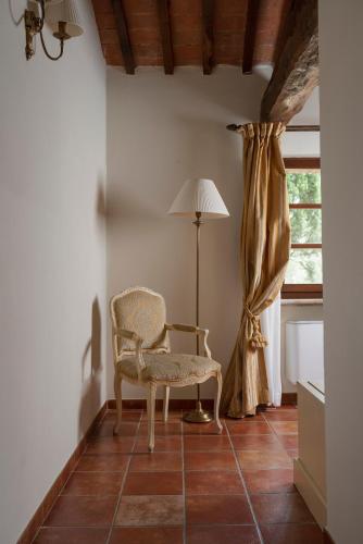 a chair in a room with a lamp and a window at Castello di Leonina Relais - Adults Only in Siena