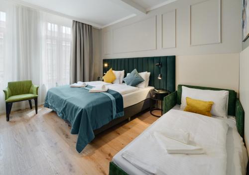 a hotel room with two beds and a chair at CHLOE Hotel Budapest in Budapest