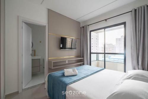 Un dormitorio con una cama y una ventana grande. en Apto 2Hab c/ balcón, próx. playa Itapema RGO702, en Meia Praia