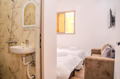 a room with four beds and a sink and a mirror at Tifawine Stay Guest House Social Stay and Oceanview Rooms in Imsouane