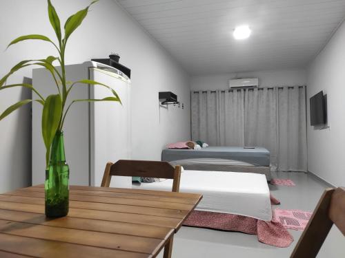 a room with two beds and a table with a plant at Apartamento Nami in Cacoal