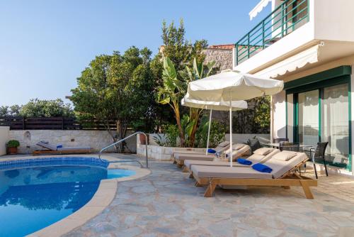 a pool with lounge chairs and an umbrella next to a house at Villa Dafni with Private Pool in Gouves