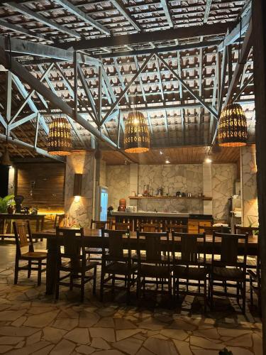 a restaurant with wooden tables and chairs and chandeliers at Pousada do Dione in Delfinópolis