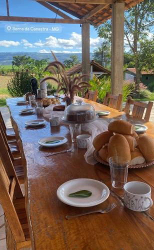 einen langen Holztisch mit Teller Essen drauf in der Unterkunft Pousada do Dione in Delfinópolis