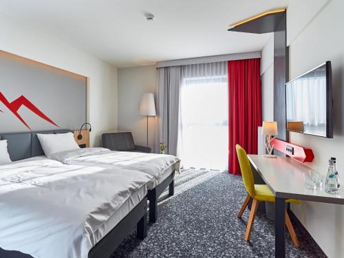 a hotel room with two beds and a desk at ibis Styles Nowy Targ in Nowy Targ