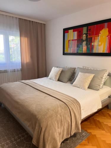 a bedroom with a large bed with a painting on the wall at Stadthaus Apartment mit Garten und Parkplatz in Zagreb