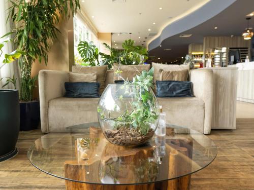a living room with a glass table with a plant in it at ibis Styles Curitiba Aeroporto in São José dos Pinhais