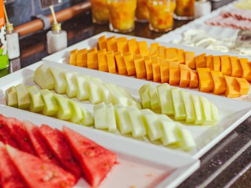 three white plates filled with different types of fruit at ibis Styles Curitiba Aeroporto in São José dos Pinhais