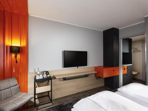 a hotel room with a bed and a tv on a wall at ibis Styles Berlin Treptow in Berlin