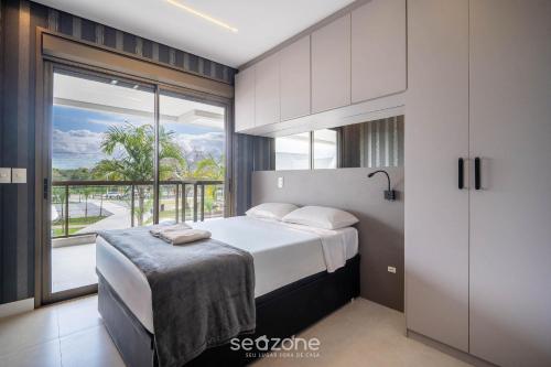 a bedroom with a bed and a large window at Apto c/ varanda e churrasqueira em Jurerê IHD0101 in Florianópolis