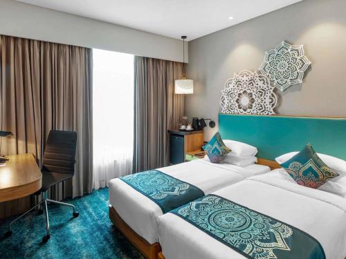 a hotel room with two beds and a desk at Grand Mercure Ahmedabad GIFT City - An Accor Hotels Brand in Gandhinagar