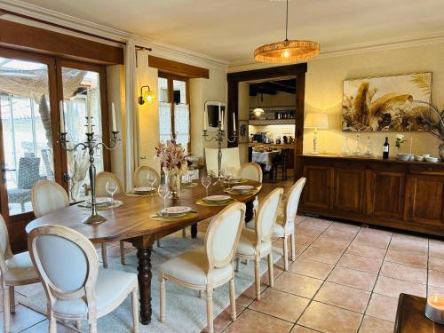 a dining room with a wooden table and white chairs at Logis de Russay in Saivres