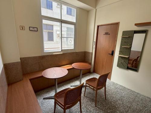 a room with two tables and chairs and a window at KM Hostel in Chiayi City