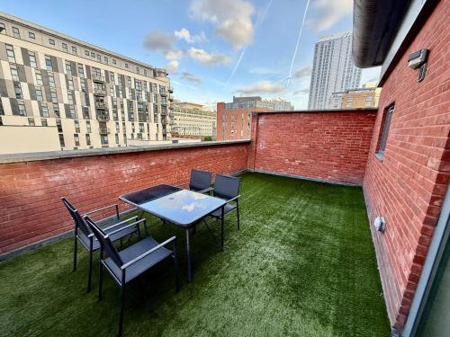 a patio with a table and chairs on a roof at Bloom Apartments - City Centre - Gated Parking in Manchester