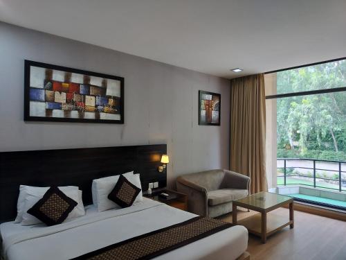 a bedroom with a bed and a chair and a window at Stellar Resorts By Bel-La Monde, Rajokri, Near IGI Airport, Delhi in New Delhi