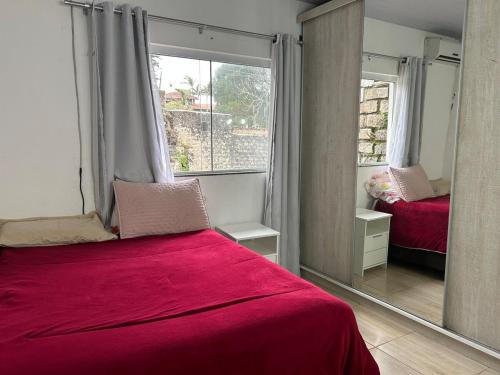 a bedroom with a red bed and a large mirror at House in Santo Antônio in Florianópolis