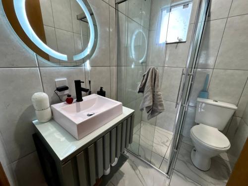 a bathroom with a sink and a toilet and a mirror at House in Santo Antônio in Florianópolis