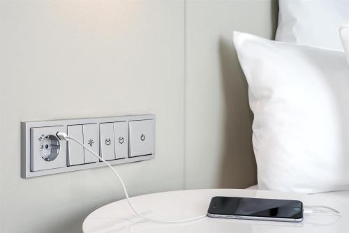 a cell phone on a table next to a pillow at NH Collection Berlin Mitte Friedrichstrasse in Berlin