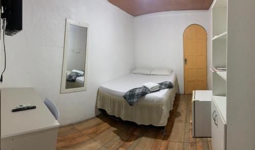 a small bedroom with a bed and a mirror at Hotel Raiz in Manaus