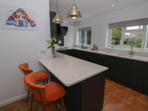 a kitchen with a white counter and orange chairs at Harran in Peopleton