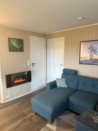a living room with a blue couch and a fireplace at Arctic Apartment in Tomasjorda