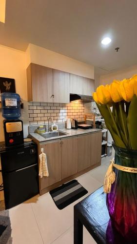 a kitchen with a vase of yellow flowers on a table at Stylish and Cozy Earth-tone Studio at Inspiria with Balcony and City-View Free WiFi and Netflix beside Abreeza Mall in Davao City