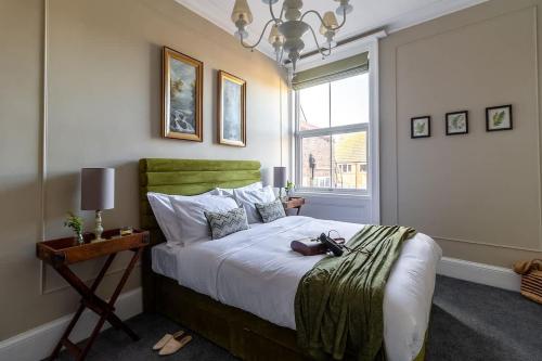 a bedroom with a bed with a green headboard and a window at Crescent View Central & Quiet Sleeps 4 in Scarborough