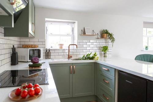 a kitchen with green cabinets and a plate of fruit at Ivy Mews - Converted Barn in Popular Village in Scarborough