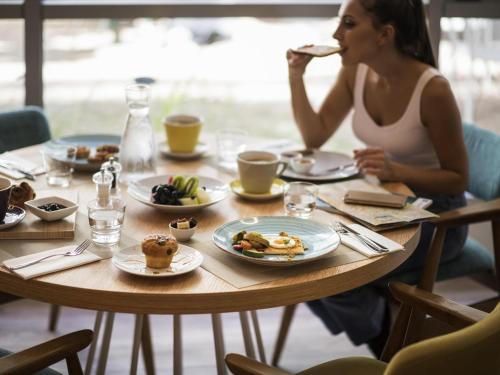 a woman sitting at a table eating food at ibis Styles Athens Routes in Athens