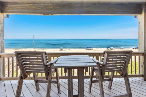 a table and two chairs on a deck with the beach at PW20 - Sea View in Southern Shores