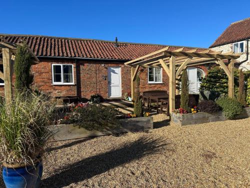 a house with a wooden pergola in a yard at Martinmas Cottage in Flamborough