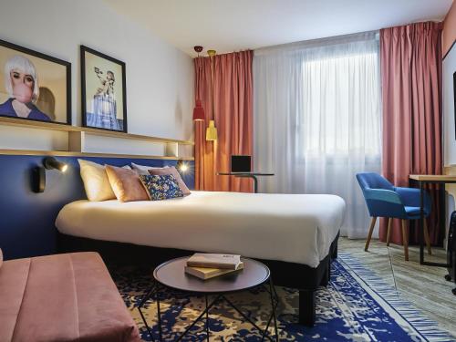 a hotel room with a bed and a couch at Ibis Styles Paris Gennevilliers in Gennevilliers