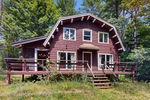 a small wooden house with a large porch in a field at Cabin on the Ridge in Tinkerville
