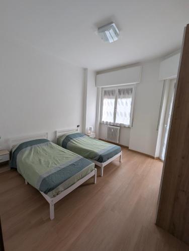 two beds in a room with white walls and wooden floors at Rholiday in Rho