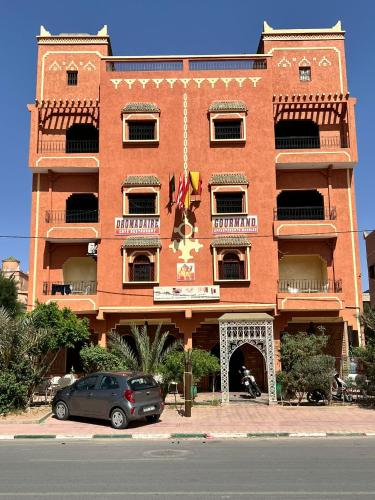 a red brick building with a car parked in front of it at Dromadaire Gourmand in Zagora