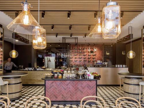 a restaurant with a bar with chairs and lights at ibis Styles Kraków East in Kraków